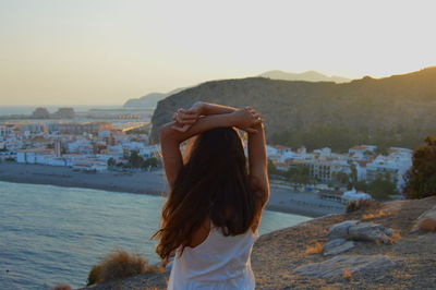 Woman standing on beach against sky during sunset