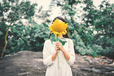 Woman holding yellow flower