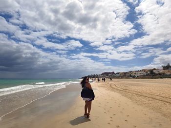 Woman standing on beach against sky