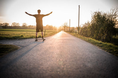 Rear view of man walking on road against sky