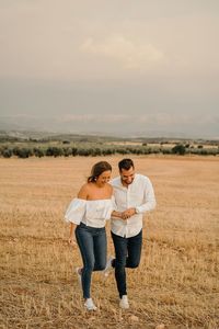 Full length of a smiling young couple on field