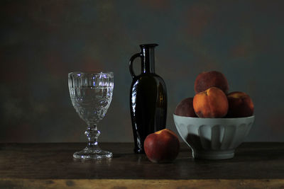 Still life composed of objects and fruit on wooden table and white cloth