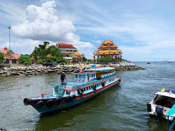 Ferry boat in the sea with chinese temple in background