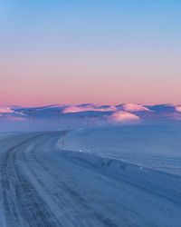 Scenic view of snow covered landscape against sky at sunset