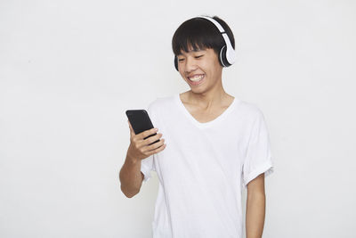 Smiling young man using smart phone against white background