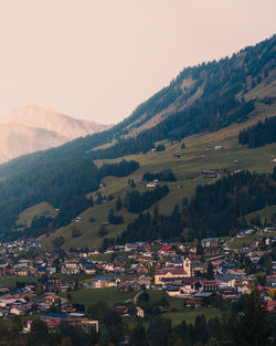 Aerial view of townscape by mountains against sky