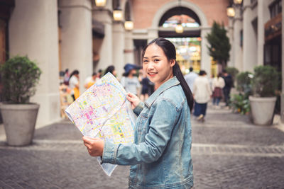 Portrait of smiling man holding umbrella in city