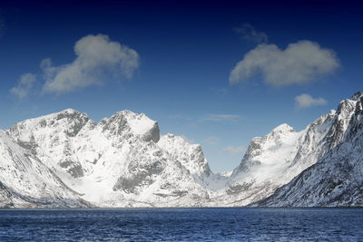 Scenic view of lake by snowcapped mountains against sky