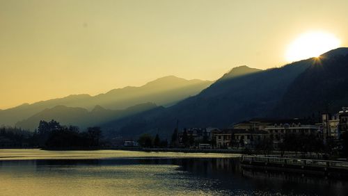 Scenic view of river by mountains against sky during sunset