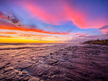 Scenic view of sea against dramatic sky during sunset