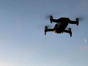 Low angle view of drone flying against clear sky