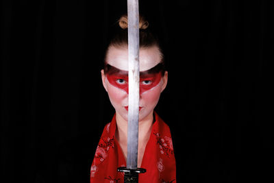 Portrait of woman with red umbrella against black background