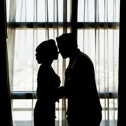 Silhouette man and woman standing against window