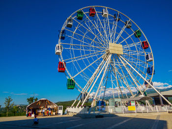 Low angle view of ferris wheel against blue sky