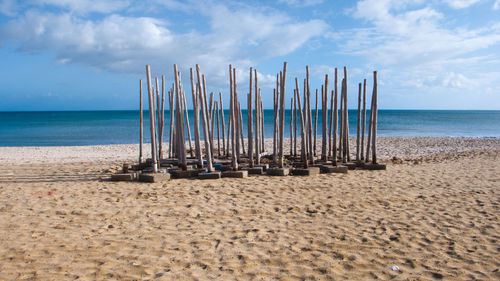 Deck chairs on beach against sky