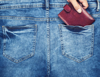 Cropped hand removing wallet from jeans pocket