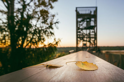 Close-up of wooden table against sky during sunset