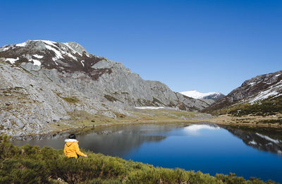 Rear view of man by lake against sky