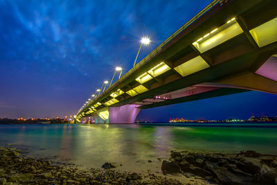 Illuminated bridge over river against sky at night