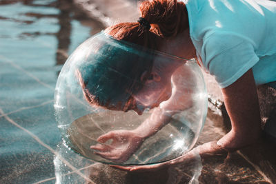 Close-up of woman wearing glass container at lake