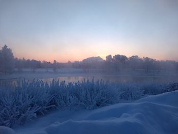 Scenic view of snow covered landscape against sky during sunset