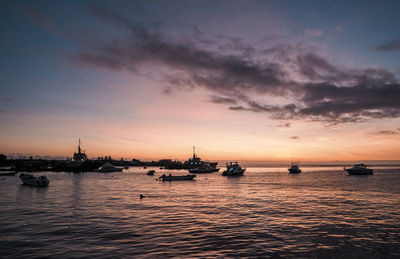 Sailboats in sea against sky during sunset