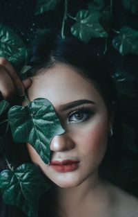 Portrait of young woman wearing make-up by plants