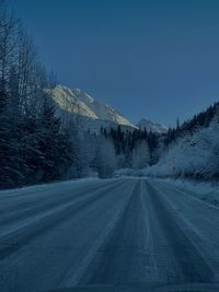 Road amidst snowcapped mountains against sky