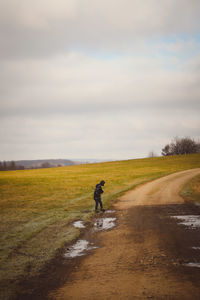 Full length of boy standing on dirt road against field