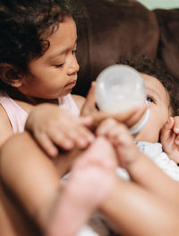 Cute sister feeding brother at home