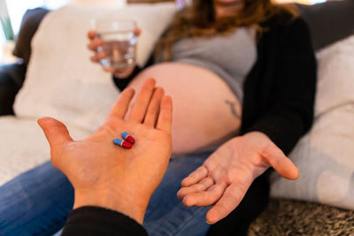 Cropped image of man giving capsules to pregnant woman