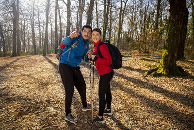 Young smiling couple is hiking in the woods. the man points the right way to his girlfriend. 