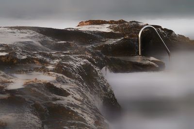 Close-up of rock formation in sea against sky