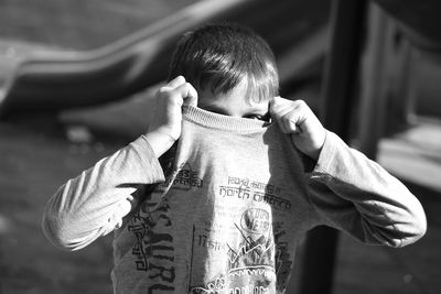 Boy removing t-shirt at park