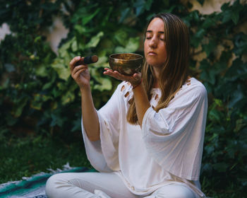 Young woman drinking drink sitting outdoors