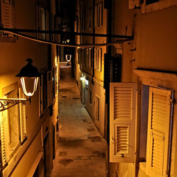 Illuminated alley amidst buildings at night