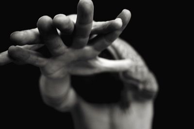 Close-up of cropped hand against black background