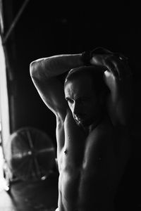 Fit young man stretching in a garage with a fan