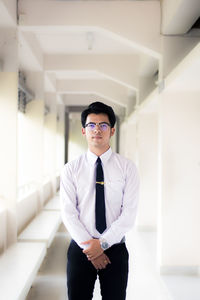 Portrait of young man standing at corridor