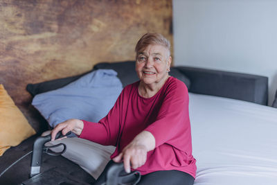 Portrait of young man sitting on bed at home