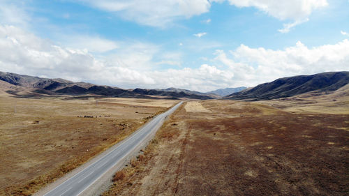 Road leading towards mountains against sky