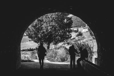 Rear view of silhouette people walking in tunnel