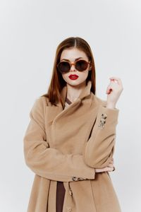 Portrait of young woman wearing sunglasses against white background