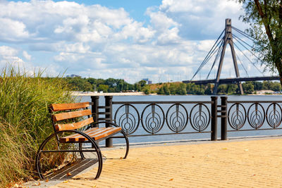 A wooden bench on the embankment of the dnipro river against the background of yellow paving slabs .