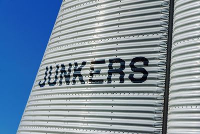 Low angle view of text on building against clear blue sky