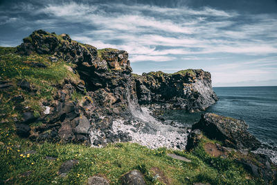 Rock formation on sea shore against sky