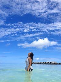 Woman standing in sea against sky