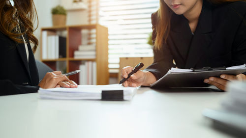Midsection of woman using mobile phone at table
