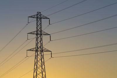 Low angle view of silhouette electricity pylon against sky during sunset