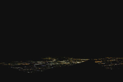 Illuminated cityscape against sky at night